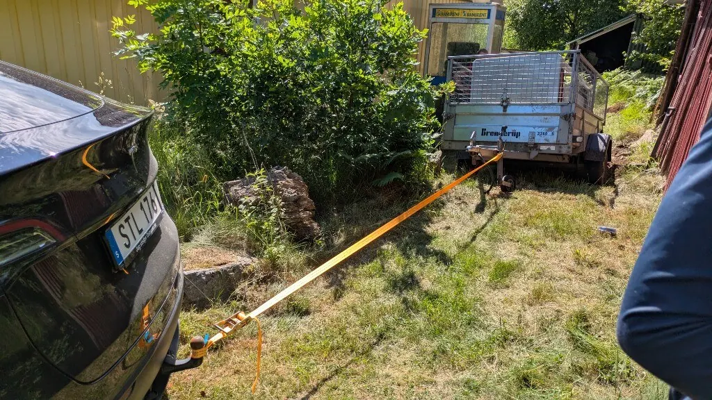 Towing the concrete booth home on a trailer with an orange strap, in daylight